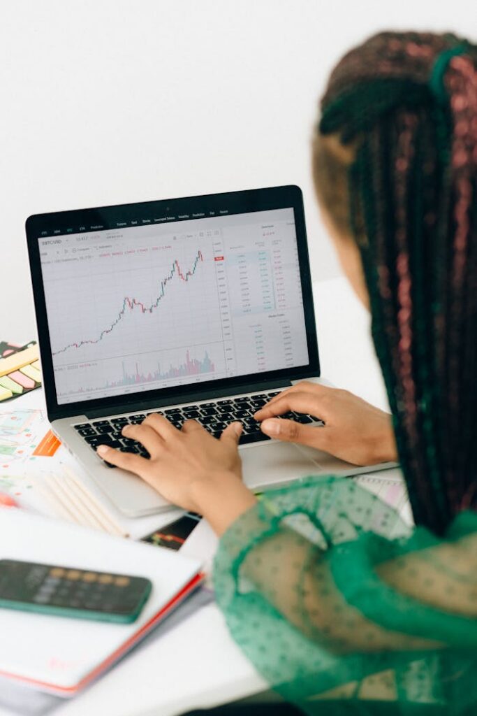 pexels photo 7172832 A woman working on financial analysis using a laptop with a stock market graph on screen.
